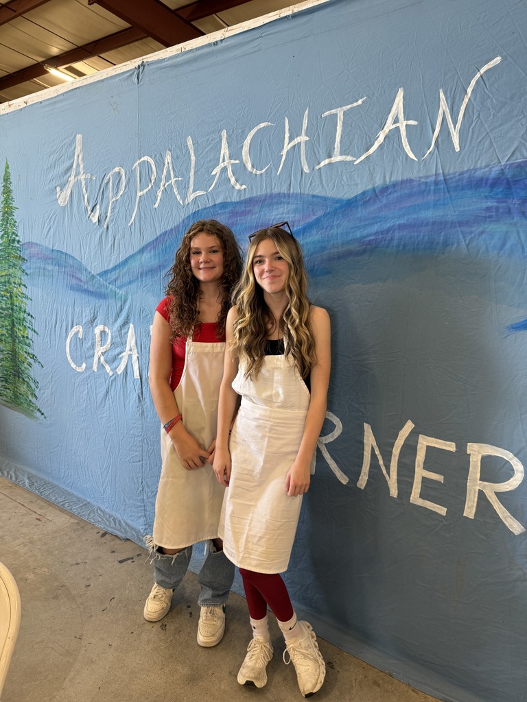 Two students pose in front of a sign that says "Appalachian Craft Corner."