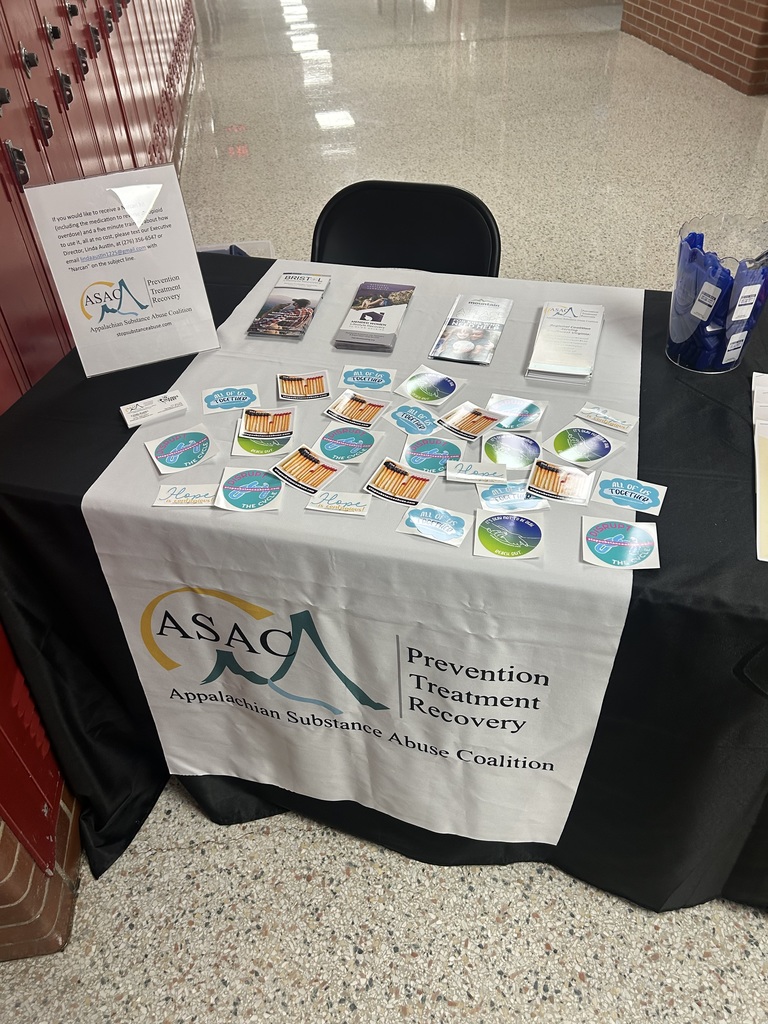 A table of free items from Prevention Treatment Recovery sits in a hall.