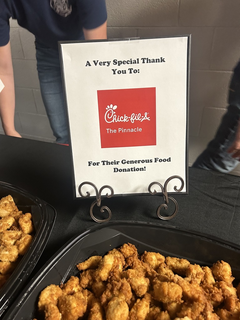 A sign thanking Chick-Fil-A sits on a table next to chicken.
