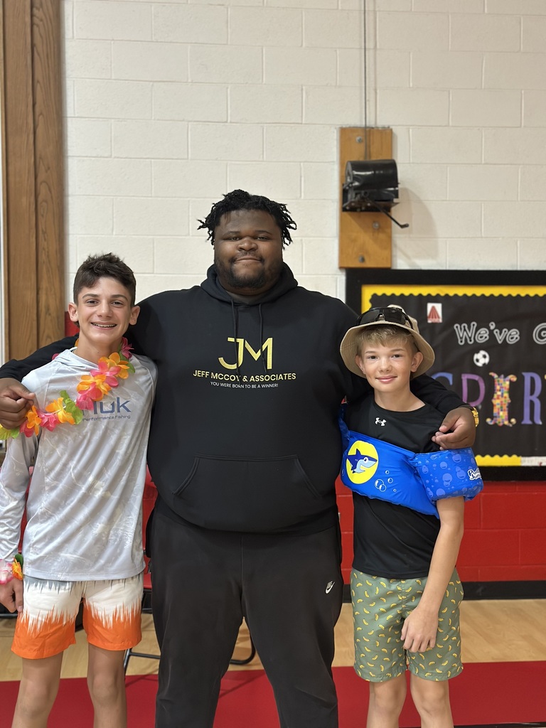 A man stands with students in a gym.