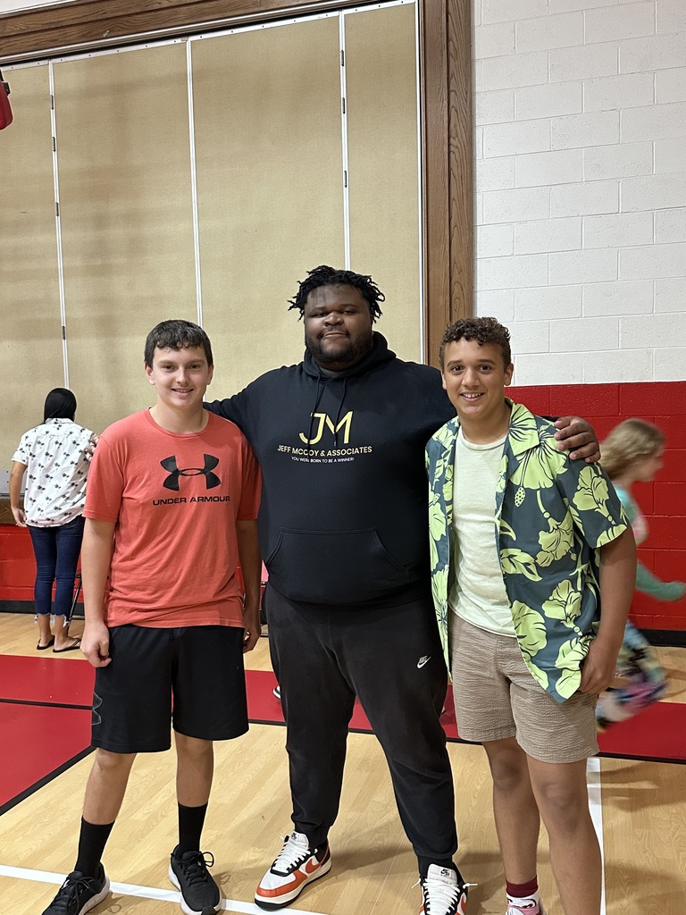 A man stands with students in a gym.