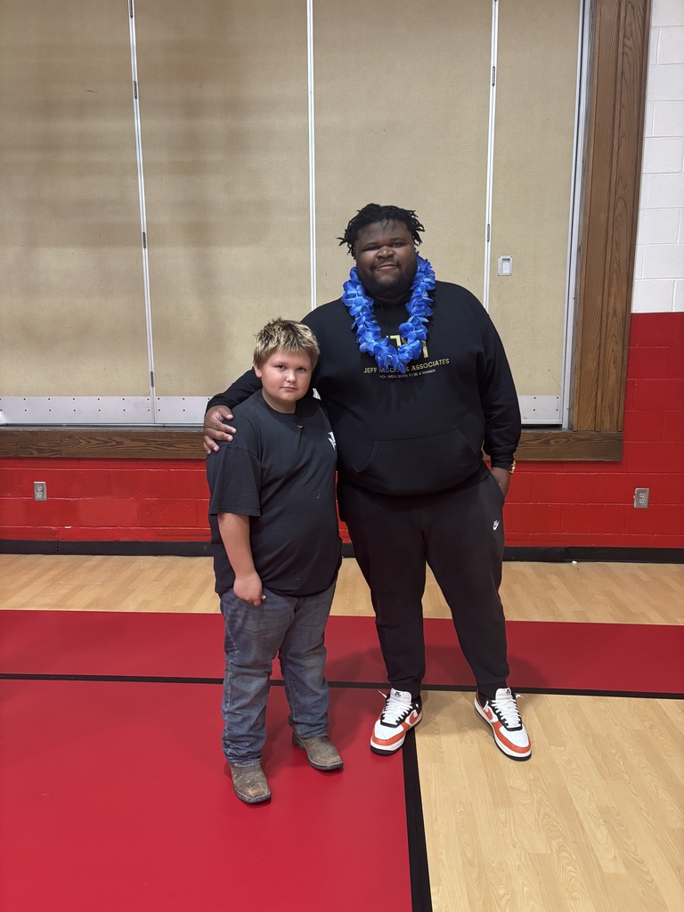 A man stands with students in a gym.