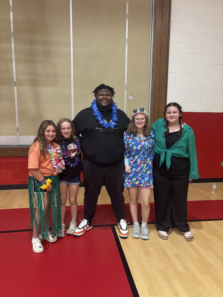 A man stands with students in a gym.