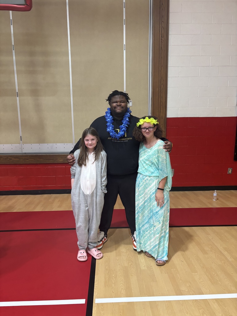 A man stands with students in a gym.