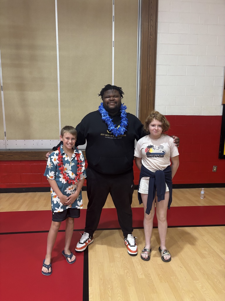 A man stands with students in a gym.