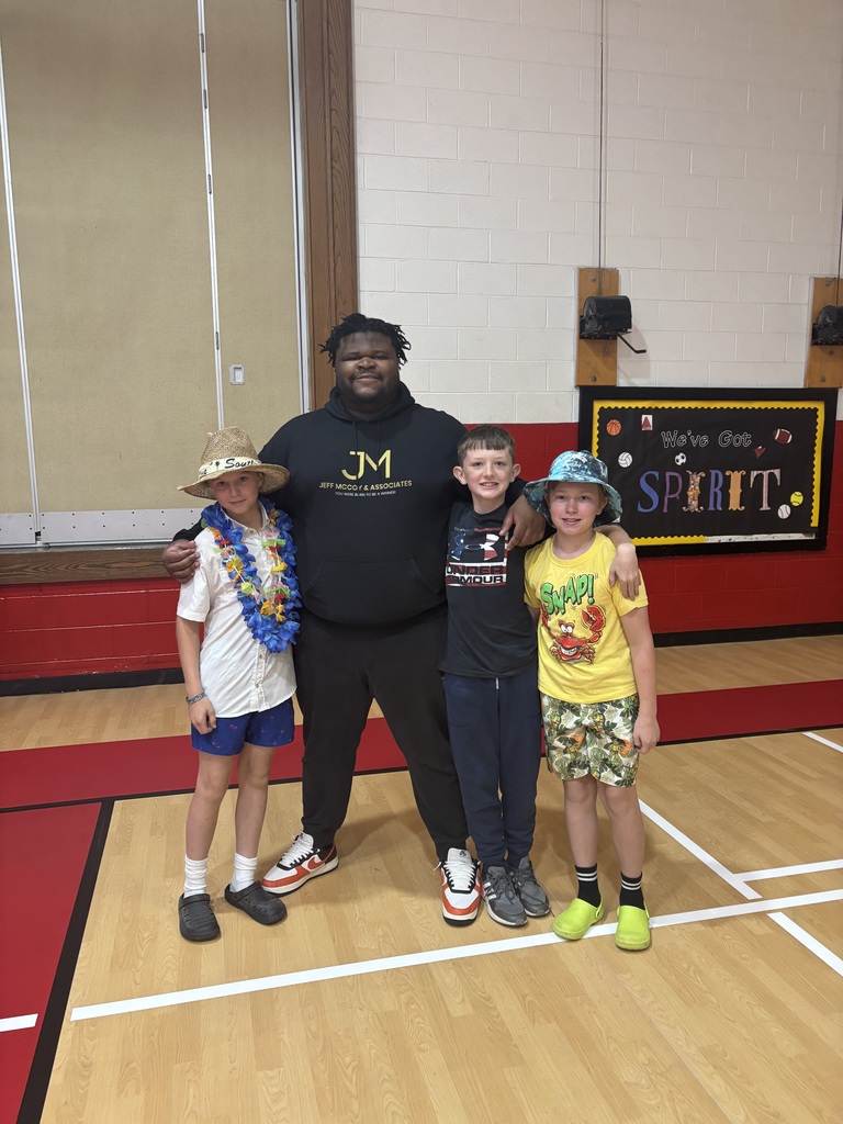 A man stands with students in a gym.