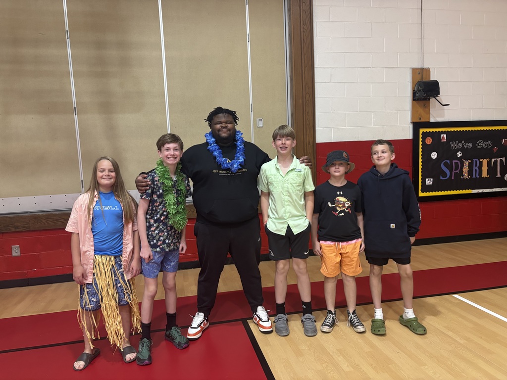A man stands with students in a gym.