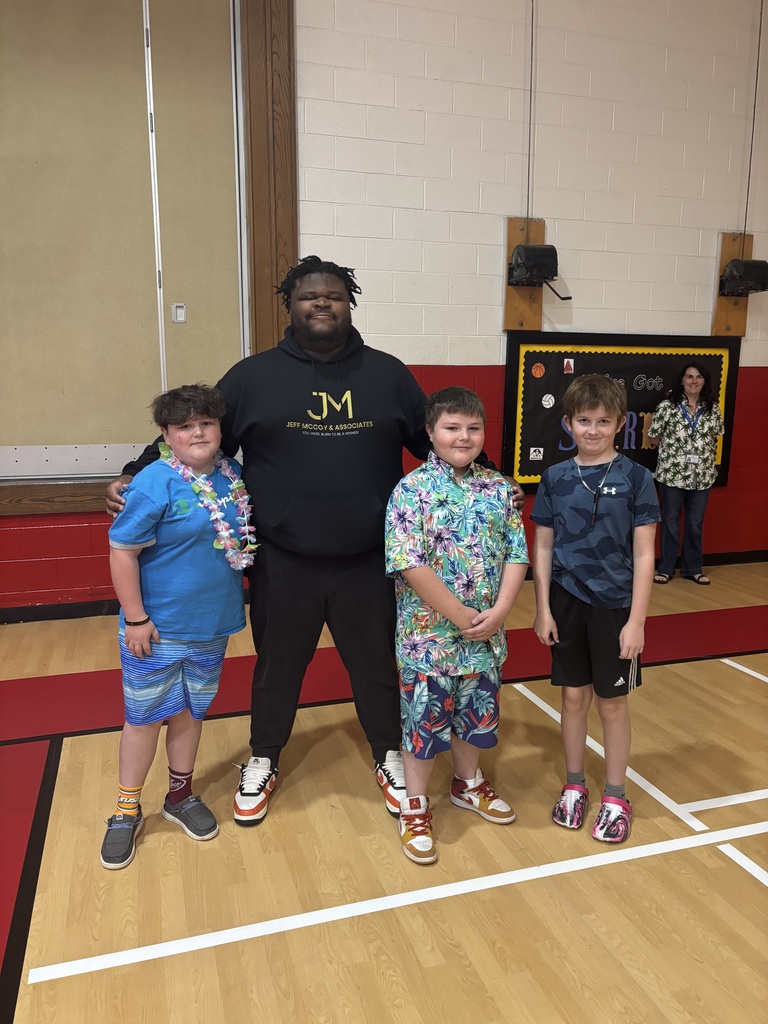 A man stands with students in a gym.