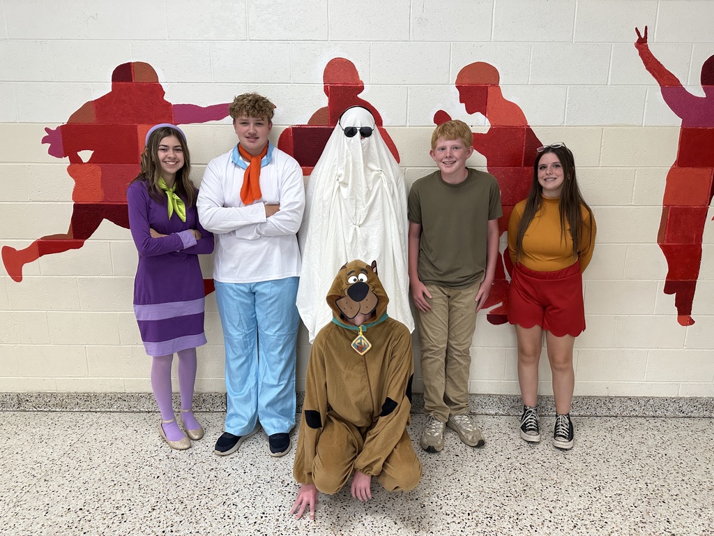 Students in costume pose in a school.
