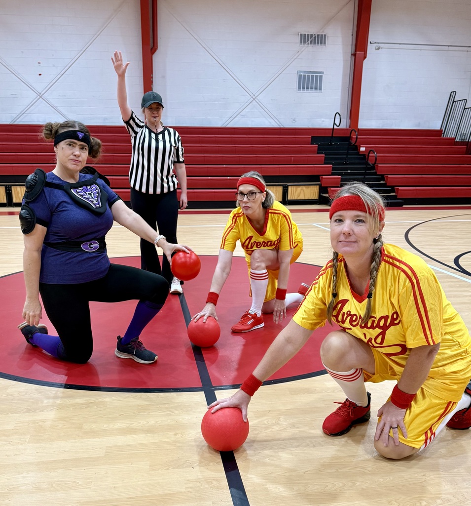 Teachers in costume pose in a school. 
