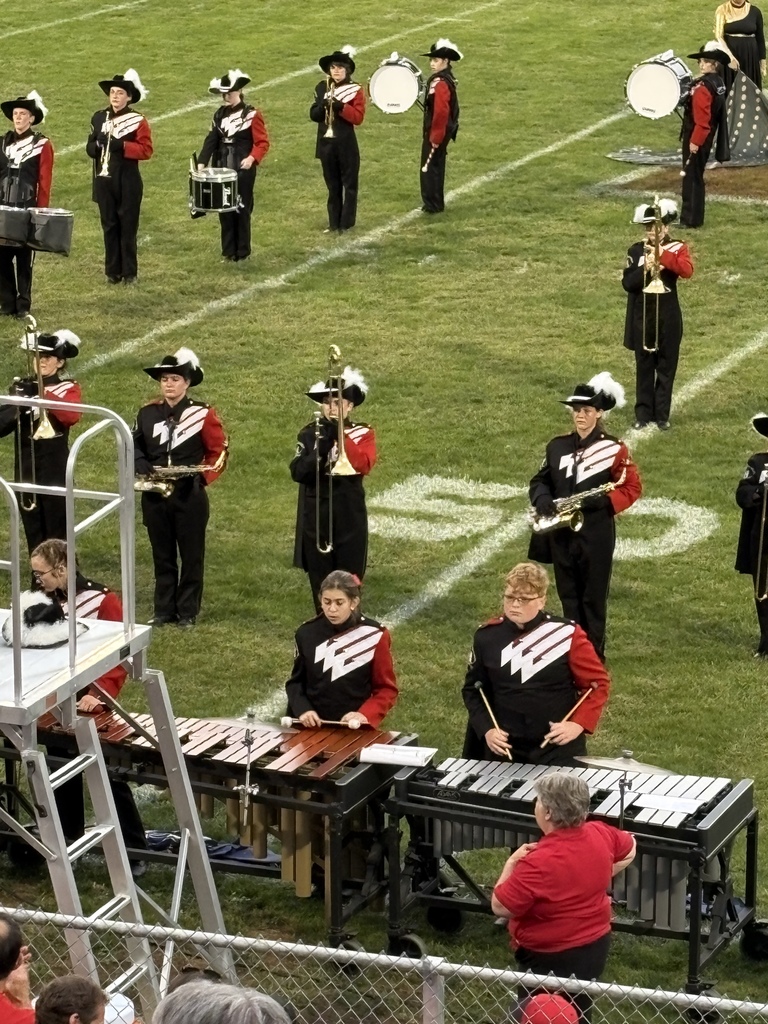 Two students play xylophone on a football field.