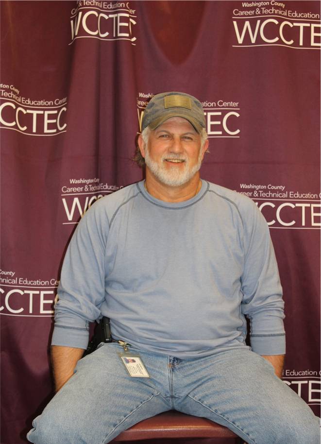 A man poses in front of a WCCTEC background.