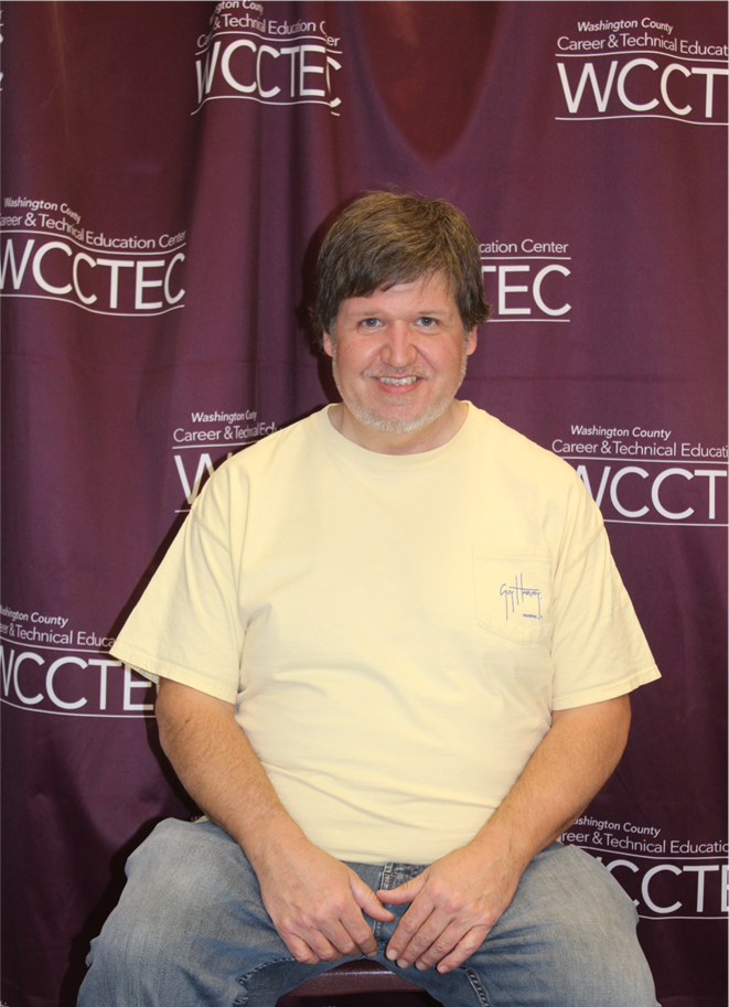 A man poses in front of a WCCTEC background.