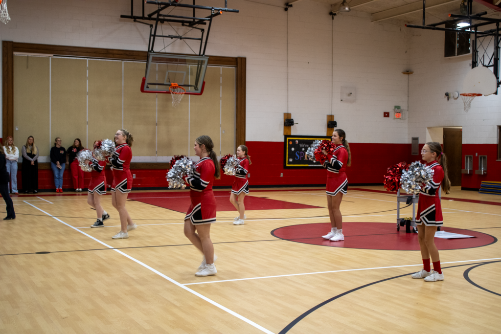 Cheerleaders cheer in a gym.