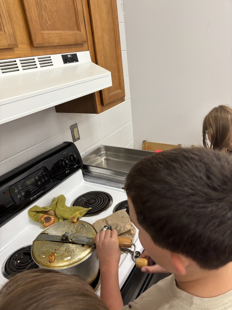 Students pop popcorn on a stovetop.