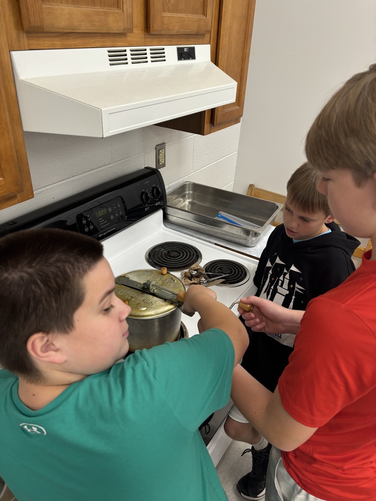 Students pop popcorn on a stovetop.
