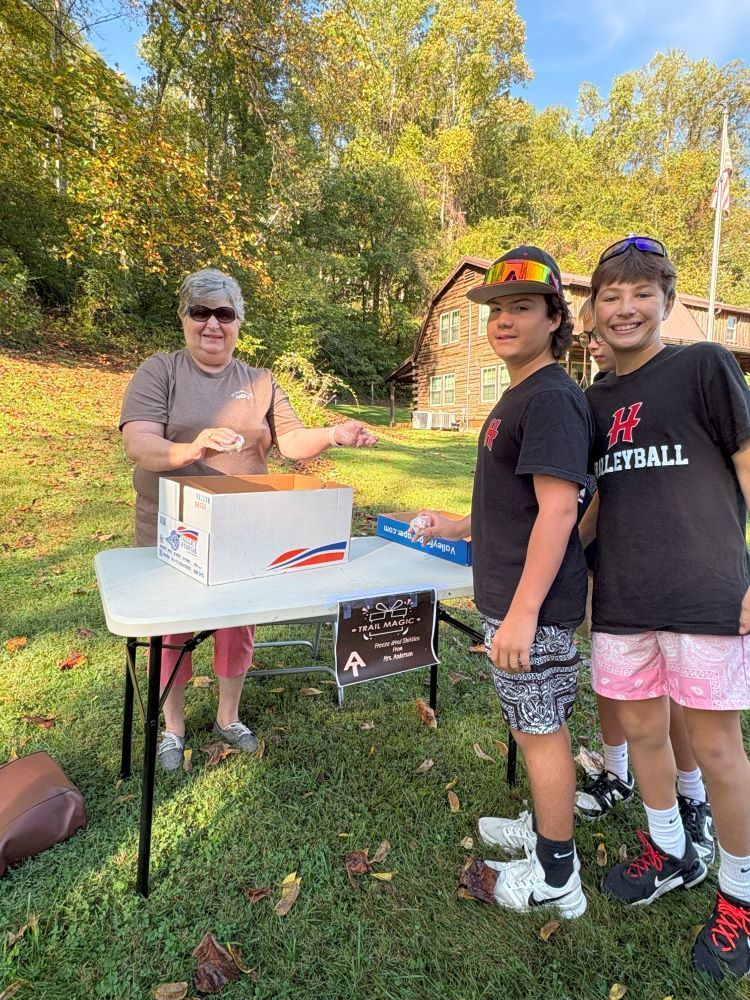A woman gives two students some candy before they walk on a trail.