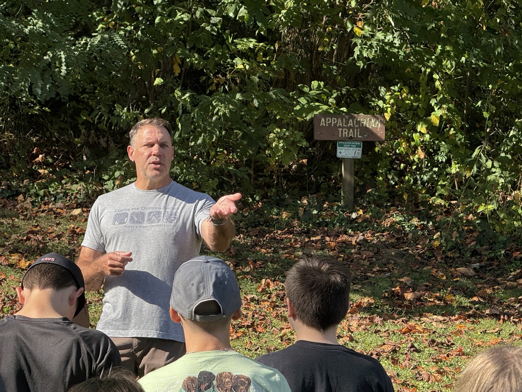 A man talks to students in front of an Appalachian Trail sign.