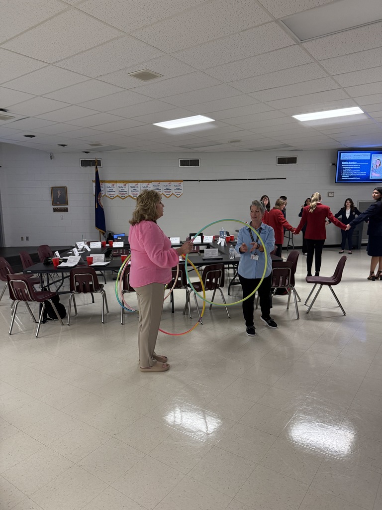 Two women hold hula hoops as they explain a game to students.