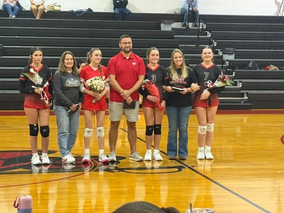 Student athlete(s) stand with teacher(s) on a court/field.