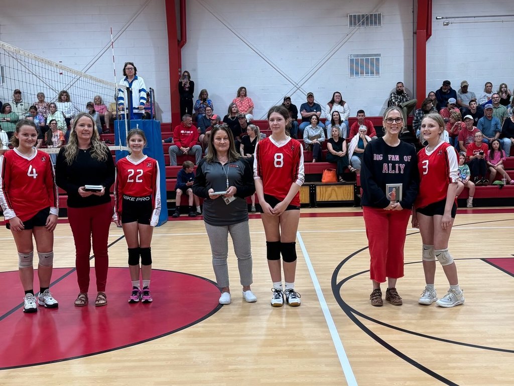 Student athlete(s) stand with teacher(s) on a court/field.