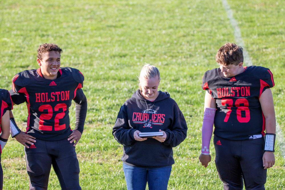 Student athlete(s) stand with teacher(s) on a court/field.