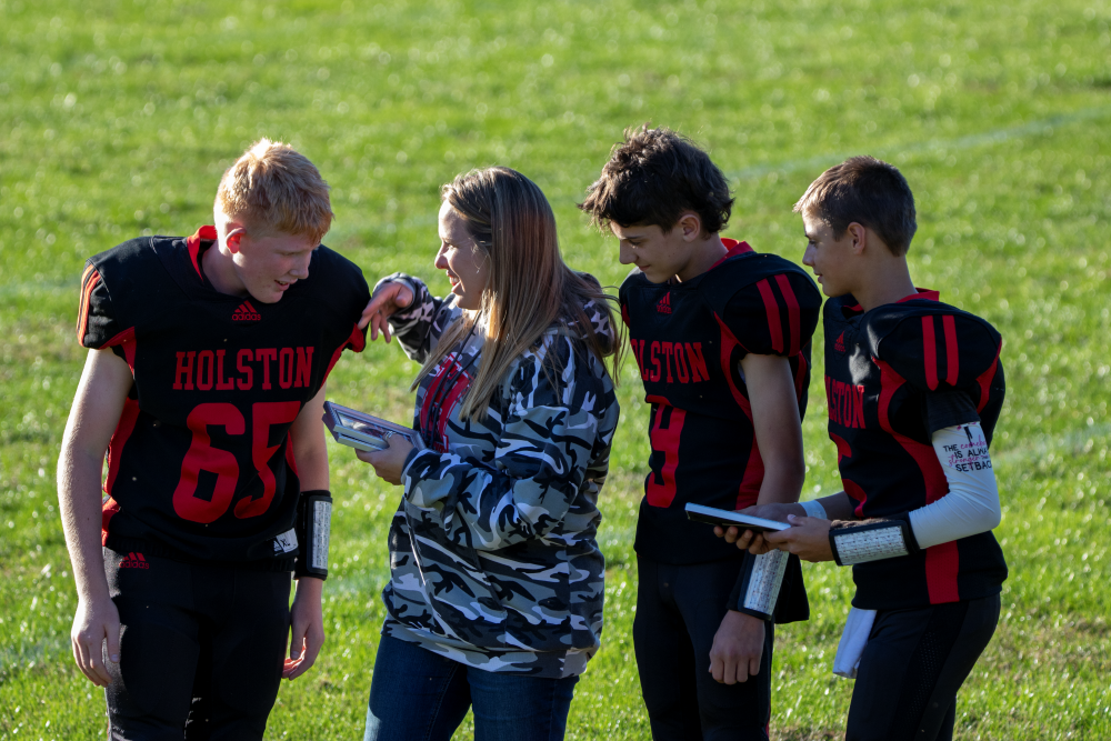 Student athlete(s) stand with teacher(s) on a court/field.