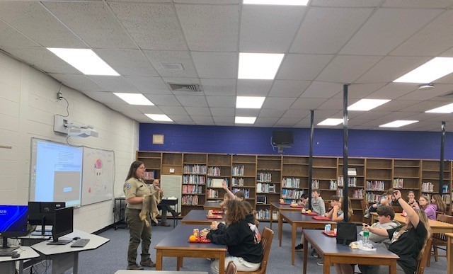 Students listen to park rangers while eating lunch.