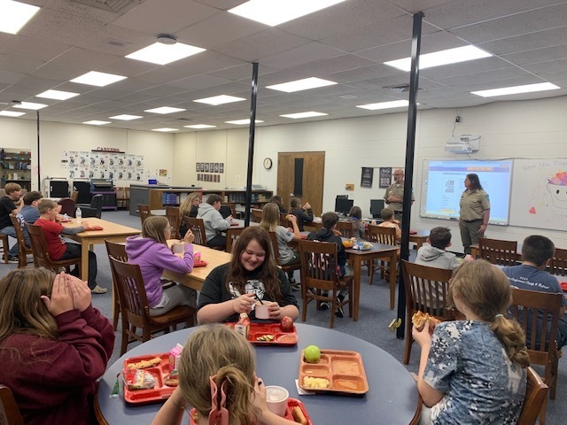 Students listen to park rangers while eating lunch.