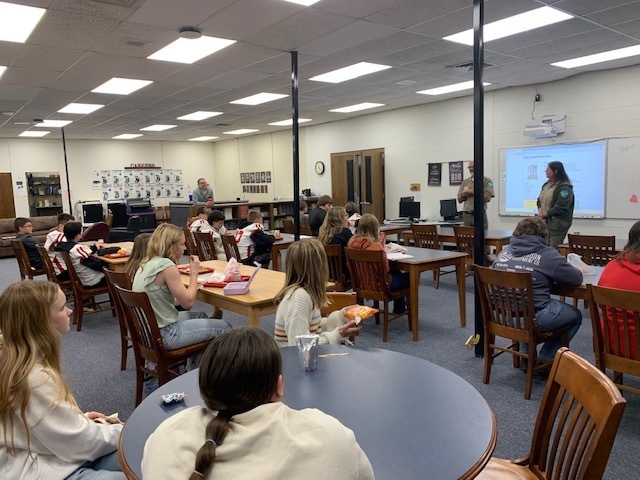 Students listen to park rangers while eating lunch.