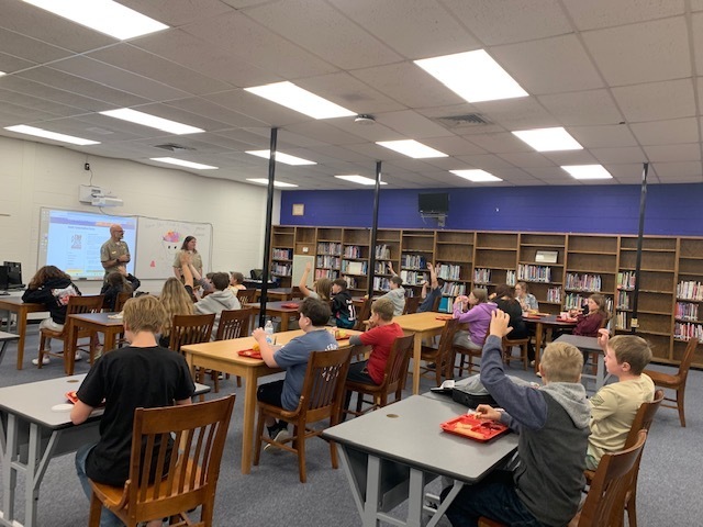 Students listen to park rangers while eating lunch.