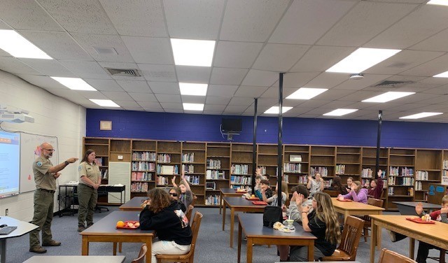 Students listen to park rangers while eating lunch.