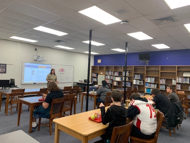 Students listen to park rangers while eating lunch.