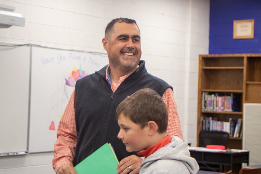 A man stands with a boy in a library.