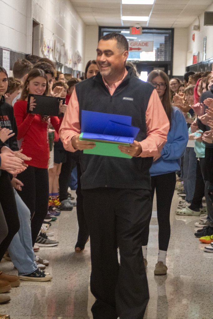 A man walks down a hall lined with children.