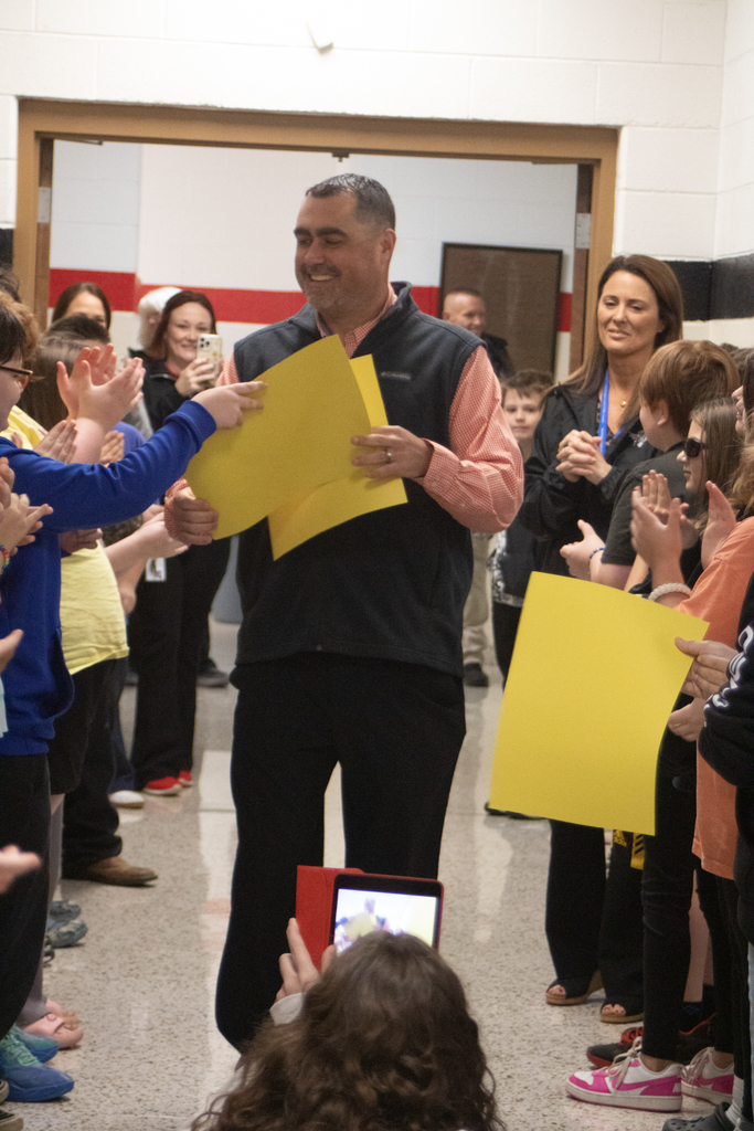 A man walks down a hall lined with students.