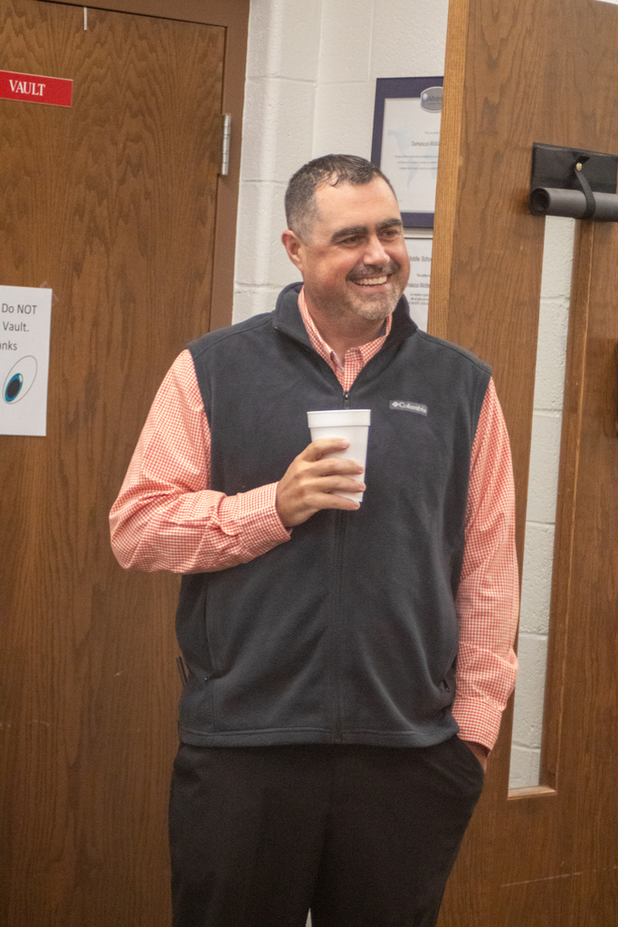 A man holds a cup of coffee in an office.