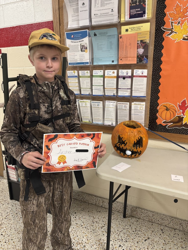 A student poses with a certificate and a carved pumpkin.