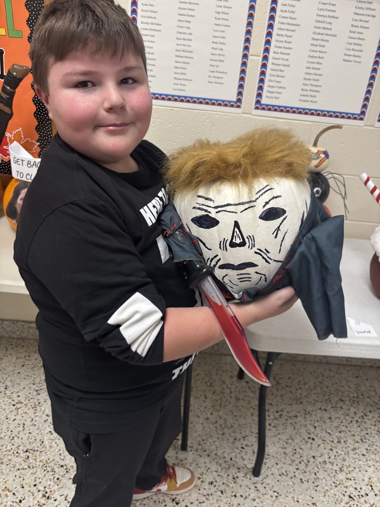 A student holds a painted pumpkin.