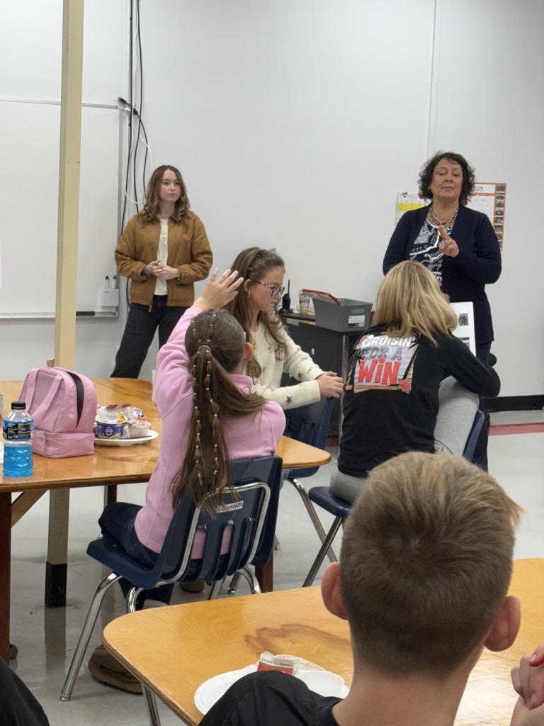 A student raises her hand to ask a question in a presentation.