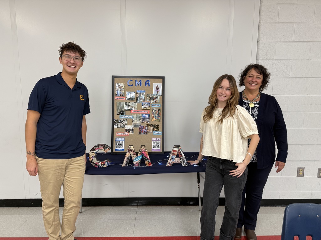 Three adults pose with a poster.