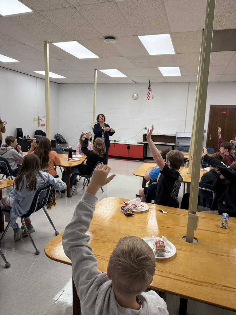 Students raise their hands to ask a woman a question.