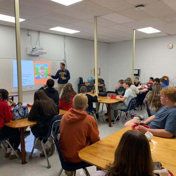 Students listen to a speaker in a classroom.