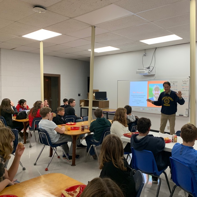 Students listen to a speaker in a classroom.