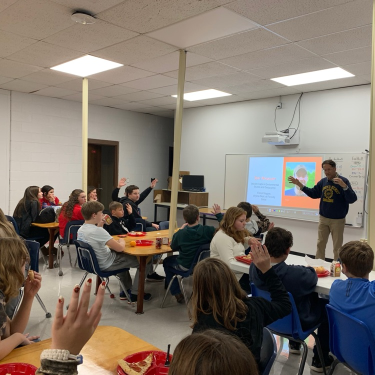Students listen to a speaker in a classroom.