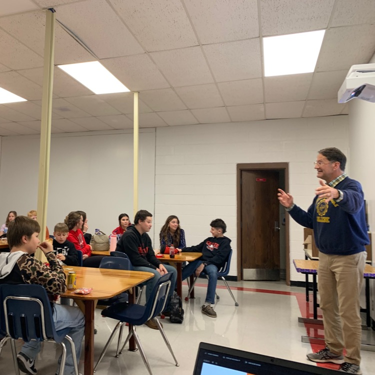 Students listen to a speaker in a classroom.