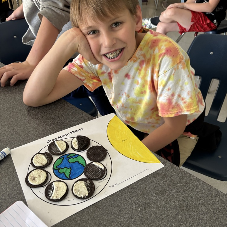 A student shows his Oreo moon phase model. 