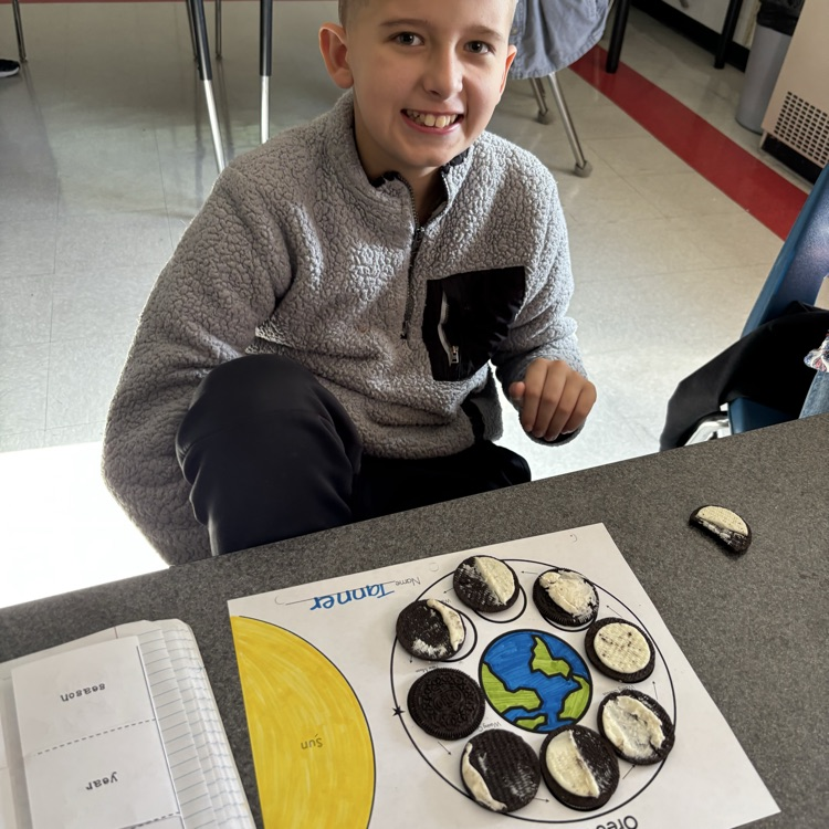 A student shows his Oreo moon phase model. 
