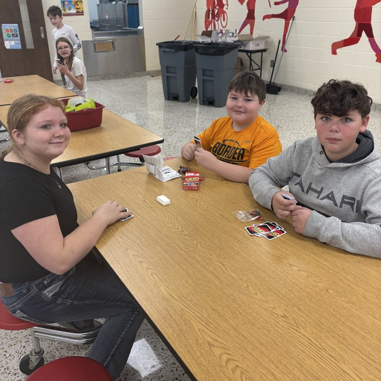 Students play UNO in a cafeteria. 