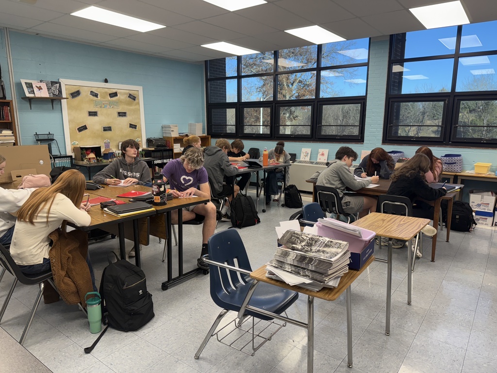 Students write letters in a classroom.